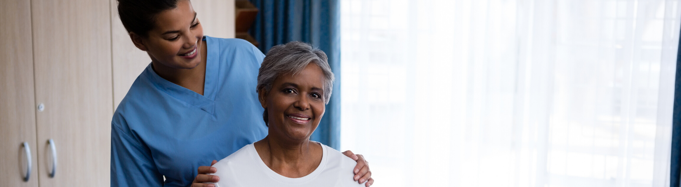 Caregiver standing with a senior client, warm smiles
